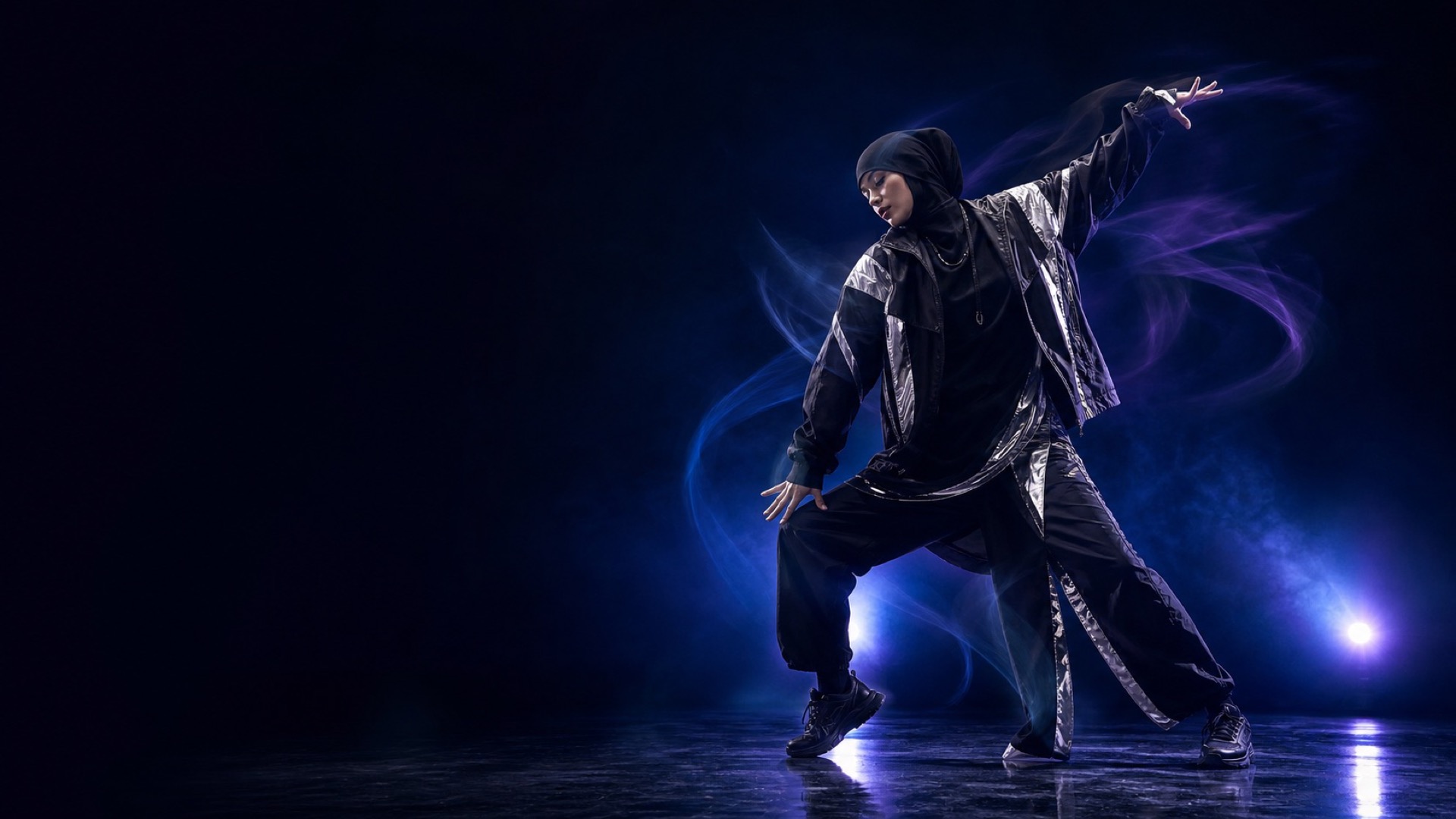 A fully clothed adult fashion dancer in a blue and violet studio